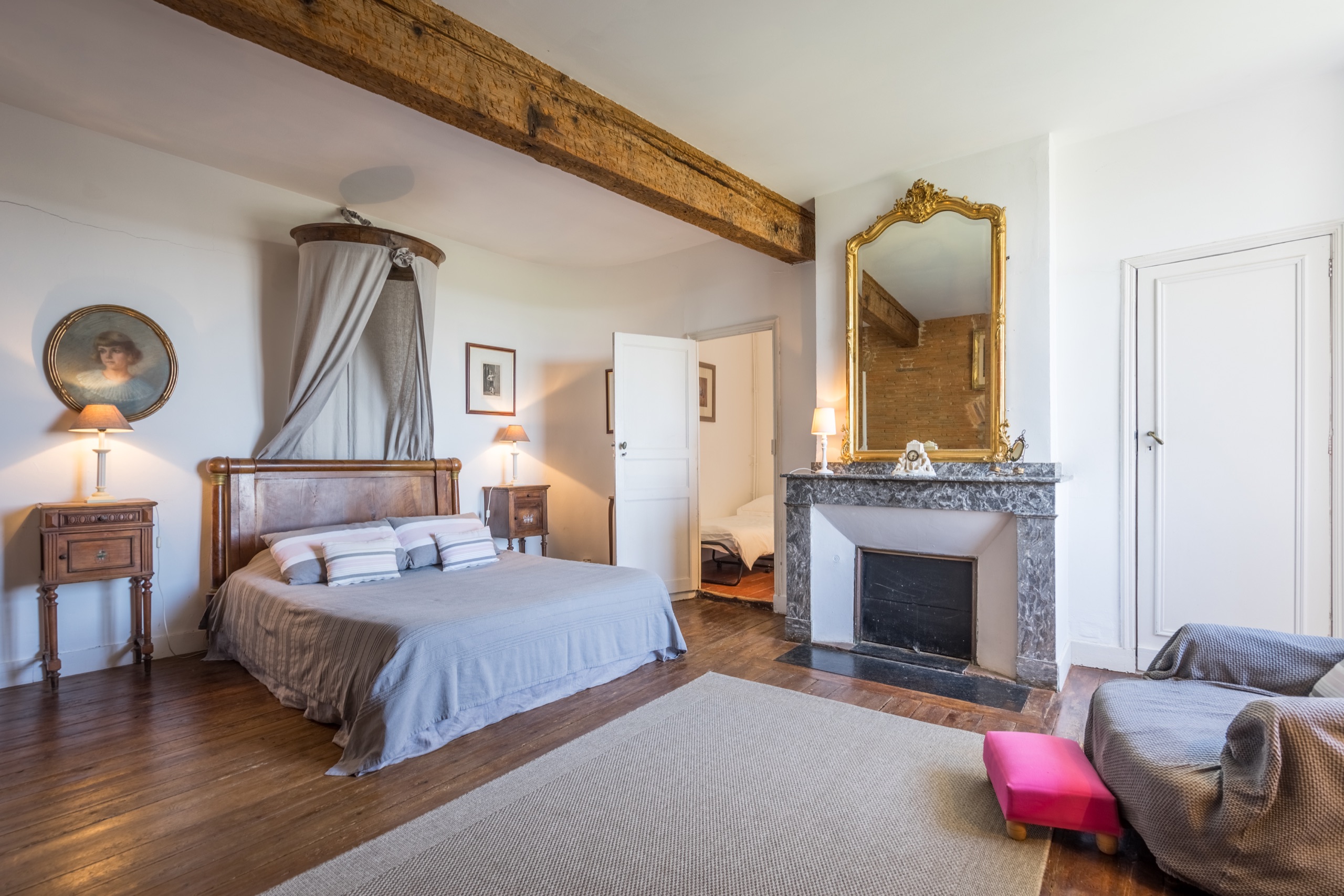 Vue principale de la Chambre de la Tour avec lit double, cheminée en pierre et poutres apparentes