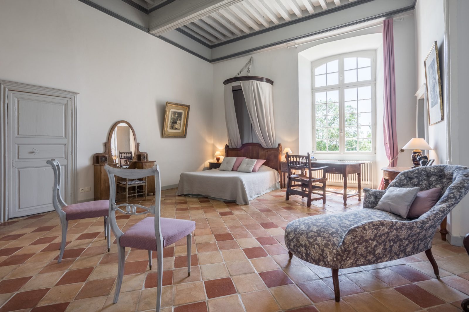 Vue large de la Chambre du Parc avec lit double, bureau ancien et chaise longue fleurie