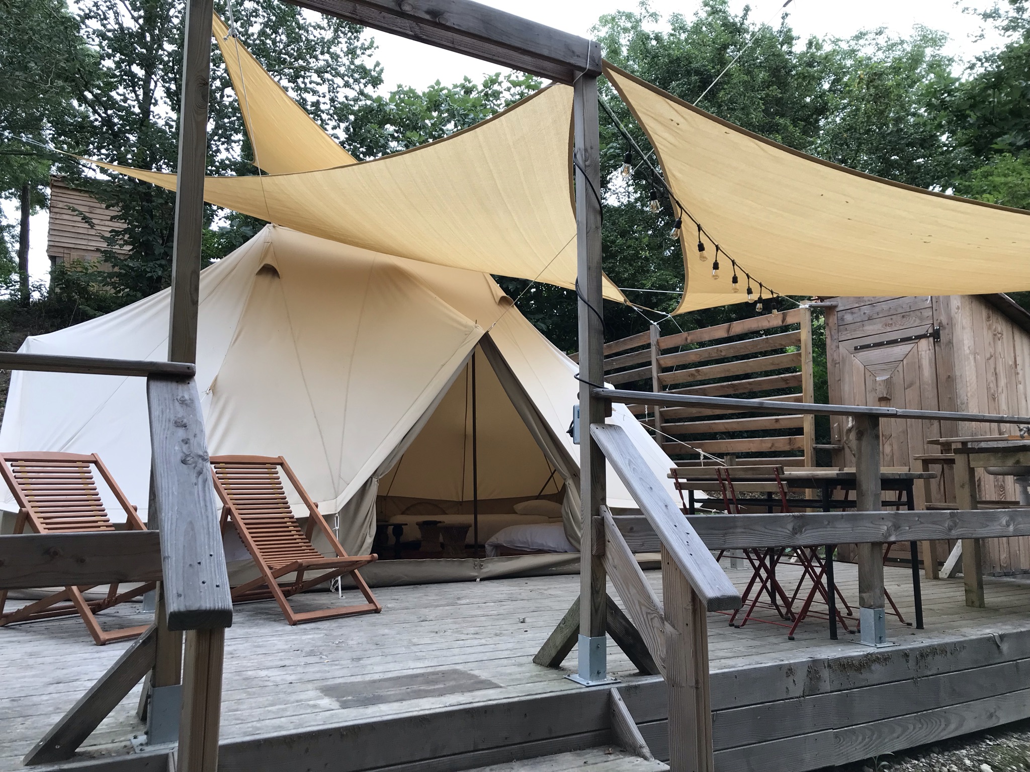 Vue extérieure du lodge Bigogne avec terrasse en bois et toile de tente