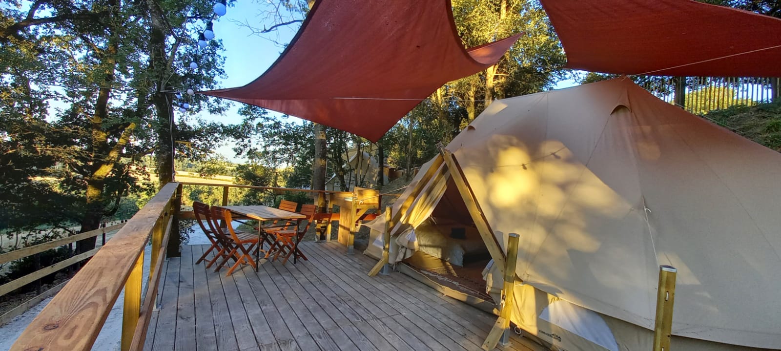 Vue extérieure du lodge Jasmin avec terrasse en bois et voiles d’ombrage rouges